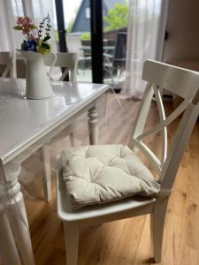 a white dining room table with a white chair with a pillow at Ferienhaus am See im Fichtelgebirge in Nagel