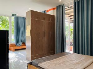a bedroom with a large wooden cabinet with blue curtains at Thanh's House Homestay Buôn Ma Thuột in Buôn Dhă Prŏng +46 photos
