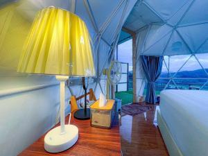 Una habitación con una cama y una lámpara en una tienda de campaña en สวนไร่รุ่งอรุณ en Ban Na Pa Paek