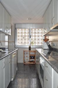 une cuisine avec des placards blancs et une grande fenêtre dans l'établissement Apartamento Boutique Hirta, à Peñíscola