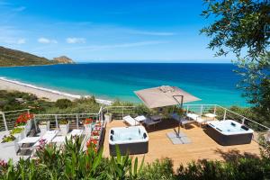 eine Terrasse mit Stühlen und einem Sonnenschirm und der Strand in der Unterkunft Emerald Hotel Residence Cefalù in Cefalú