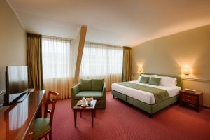 um quarto de hotel com uma cama e uma cadeira verde em Hotel Barchetta Excelsior em Como