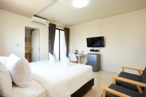 Habitación de hotel con cama blanca y TV en Bansuay Phranangklao Apartment&Hotel en Ban Sai Ma