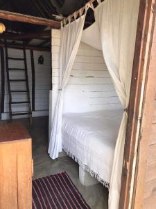 a bedroom with a bed with a canopy and a ladder at Beach front Cottage in Mahambo