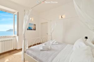 a white bedroom with a bed and a window at Oltremare, Terre Marine in Manarola