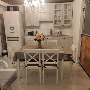 eine Küche mit einem Tisch und Stühlen sowie eine Küche mit weißen Schränken in der Unterkunft Villa Vanília in Keszthely