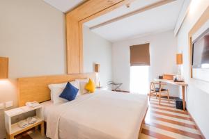 una camera da letto con un grande letto bianco con cuscini blu e gialli di The ONE Legian a Legian