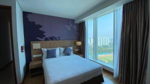 a hotel room with a bed and a large window at The H Tower Rasuna Suites Kuningan Jakarta By Villaloka in Jakarta
