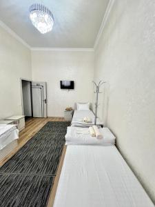 Habitación blanca con 2 camas y TV. en MrShox Hostel en Samarcanda