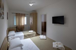 a hotel room with two beds and a flat screen tv at Elysium B&B in Mazara del Vallo