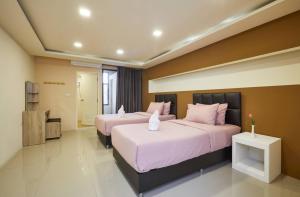 sypialnia z 2 łóżkami i różowymi poduszkami w obiekcie Bansuay Phranangklao Apartment&Hotel w mieście Ban Sai Ma