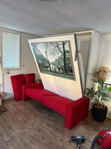 een woonkamer met een rode bank en een foto bij Boat no Breakfast in Amsterdam