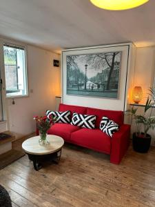 un sofá rojo en una sala de estar con mesa en Boat no Breakfast, en Ámsterdam