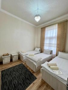 Habitación con 3 camas y ventana en MrShox Hostel, en Samarkand