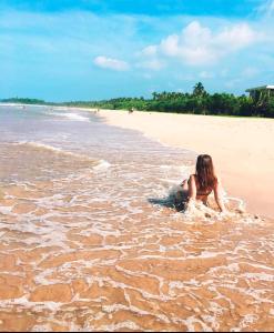 Una donna stesa in acqua su una spiaggia di Lucky Prince Villa ad Aluthgama