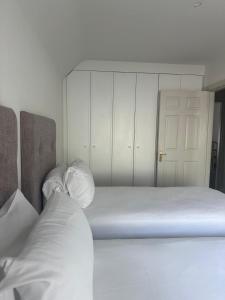 um quarto com uma cama e um armário com lençóis brancos em St Bridget's Apartments em Galway