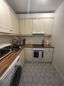 a kitchen with white cabinets and a sink and a dishwasher at St Bridget's Apartments in Galway