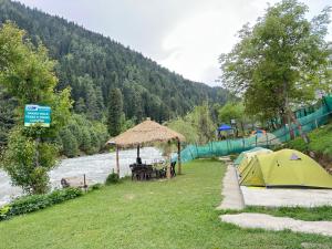 a campsite with a tent next to a river at The woodswalk Treks and tours in Pahalgām