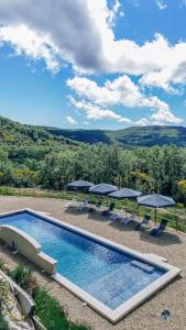 una piscina con sombrillas, sillas y mesas en Mas de Toulair, Spacieuse villa d'exception 5 étoiles, en Saint-Christol-de-Rodières