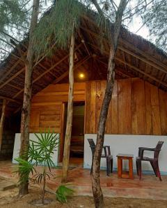 uma casa com telhado de palha e duas cadeiras em Sand Dune Beach Resort & Surf Camp em Arugam Bay