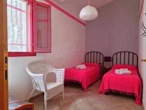 a room with two beds and a chair and a window at Dommos - Casa Sicutera in Orosei