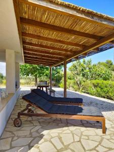 a bed under a wooden roof on a patio at Dommos - Casa Sicutera in Orosei
