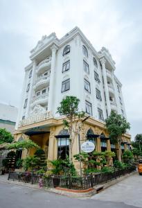 een groot wit gebouw met bomen ervoor bij Song Anh Hotel Tuần Châu in Ha Long