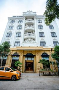 een oranje auto geparkeerd voor een gebouw bij Song Anh Hotel Tuần Châu in Ha Long