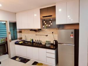 a kitchen with white cabinets and a refrigerator at Idea Homestay 3 in Chemor