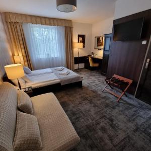 a hotel room with a couch and a tv and a desk at Oaza Resort in Stegna +38 photos