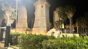 um edifício com três torres com palmeiras à noite em Salento Villa Don Peppino em San Foca