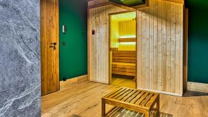 a wooden room with a bench and a green wall at OSTOJA RESIDENCE VIP ze strefą relaksu i pokojem zabaw by Royal Aparts in Szklarska Poręba