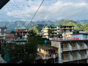 un groupe de bâtiments avec des montagnes en arrière-plan dans l'établissement Mcleodganj Diaries Homestay, à Dharamshala