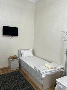 Cette petite chambre comprend un lit et une télévision murale. dans l'établissement MrShox Hostel, à Samarcande
