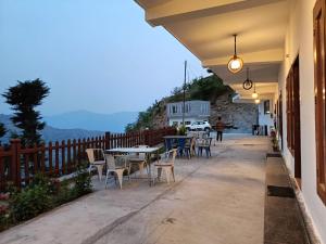 eine Terrasse mit Tischen, Stühlen und einem Zaun in der Unterkunft The Tranquil hotel in Chakrata