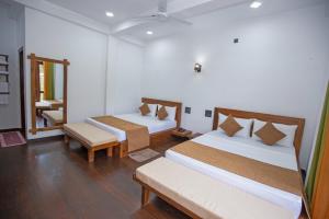 Habitación con 2 camas, silla y espejo. en Wenasa Holiday Resort, en Diyatalawa