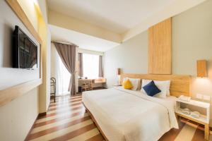 a hotel room with a bed and a television at The ONE Legian in Legian