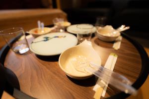 une table en bois avec des assiettes et des verres blancs dans l'établissement BIOSvilla522-Sapporo Susukino Night- 1Room W-beds2&S-beds2 6Persons, à Sapporo