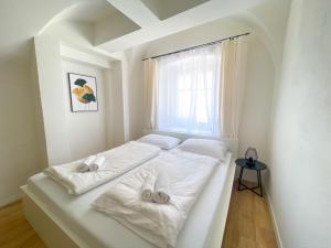ein weißes Bett mit zwei Handtüchern auf einem Zimmer in der Unterkunft StayHere Central City Suite 1 - contactless Self-Check-IN in Graz