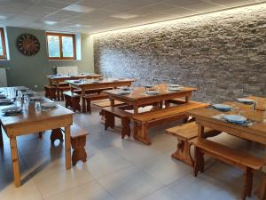 una sala da pranzo con tavoli in legno e un muro di mattoni di La Marmotte De La Meije a Le Bourg-dʼOisans