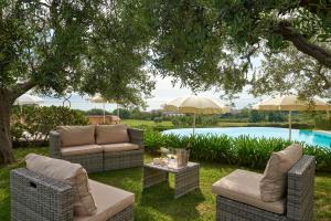a patio with two couches and a table under a tree at Pamperduto Country Resort in Porto Potenza Picena