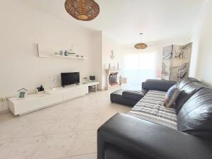 uma sala de estar com um sofá de couro e uma televisão em Estrelinha GuestHouse na Nazaré