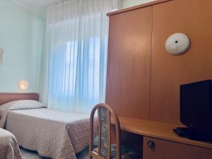 a bedroom with a bed and a desk with a television at Hotel San Giorgio in Albisola Superiore