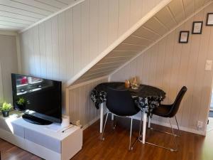 a dining room with a table and a tv and chairs at Sentrumsnært studio ved Bugården in Sandefjord