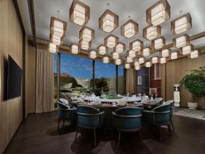 a dining room with a long table and chairs and a chandelier at Banyan Tree Suzhou Shishan in Suzhou