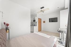 a white bedroom with a bed and a kitchen at Adore in Palanga