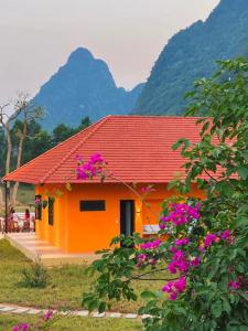 pomarańczowy dom z fioletowymi kwiatami przed nim w obiekcie Phong Nha Eco Village w mieście Phong Nha