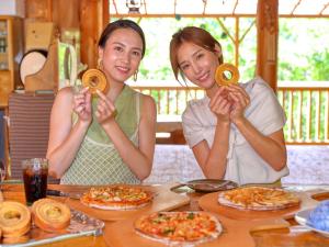 two women sitting at a table holding up doughnuts at NOHOHON PARK Hida-Osaka formerly Hida-Osaka Fureai-no-mori in Gero