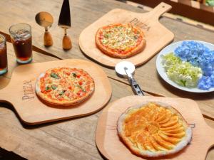 a table with three pizzas on wooden cutting boards at NOHOHON PARK Hida-Osaka formerly Hida-Osaka Fureai-no-mori in Gero