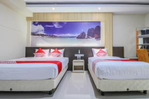 two beds in a room with a painting on the wall at Super OYO Balitone Residence in Denpasar